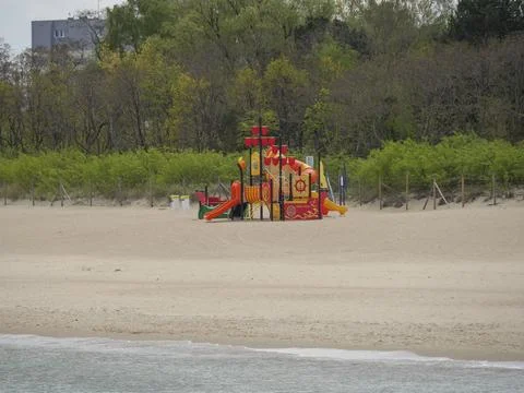 Colourful playground on a sandy beach, surrounded by nature, somewhat cloudy Stock Photos