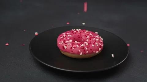 Colourful sprinkle falls on Pink Glazed Doughnut. Doughnut decoration. Slow-mo Stock Footage 237300752