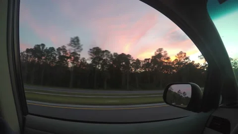 Colourful sunset viewed from inside a car driving on a motorway Video stock 153647335