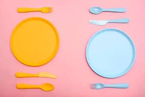 Colourful tableware for two persons on pink table. Stock Photos