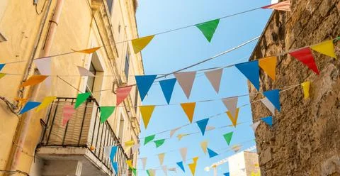 Colourful triangular bunting flags strung across a narrow old town street Stock Photos
