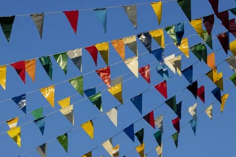 Colourful triangular flags on a rope in the air and a blue sky in the Stock Photos