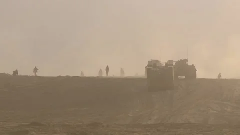 A column of armored vehicles in a combat zone in the desert, paratroopers run Stock Footage 145840245