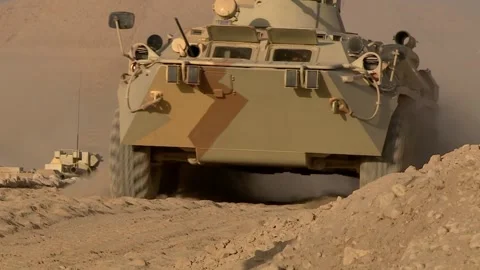 A column of armored vehicles passes through a checkpoint in the desert, a combat Stock Footage 162382246
