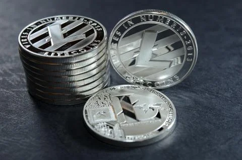 Column of litecoins with two single coin next to them on dark leather surface 스톡 사진