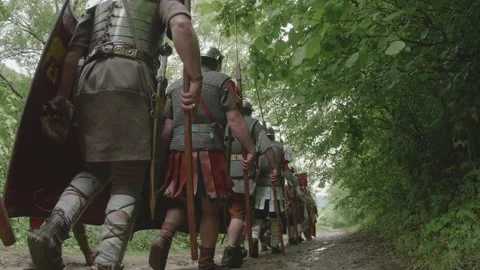 The column of Roman legionaries marching in a column on a dirt road carrying Stock-Footage 148260262