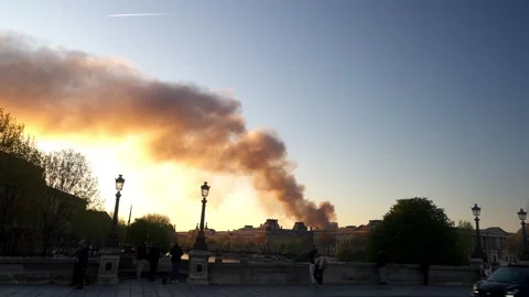 Column of smoke is seen during sunset by the Seine River in Paris Stock Footage 312872849