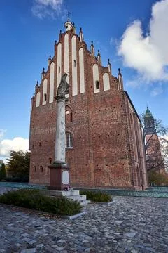 Column with statue in front of Historic, Gothic Catholic Church Stock-Fotos