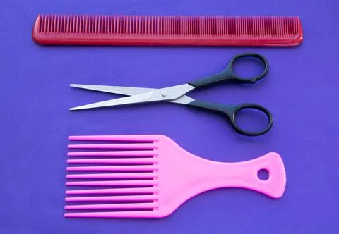 Comb and scissors on a purple background Stock-Fotos