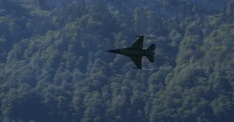 Combat Aircraft Soaring at High-Speed Low Altitude Over Green Forest. Copy Space Stock Photos