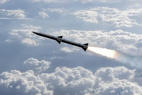 A combat rocket is flying above the clouds, smoke and fire from the rocket.  Stock Photos