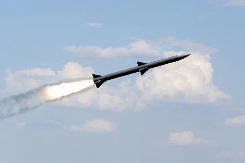 A combat rocket is flying above the clouds, smoke and fire from the rocket. 스톡 사진