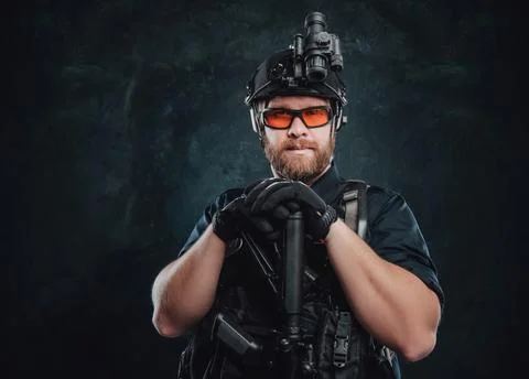 Combative man poses in dark background with rifle looking at camera Stock Photos