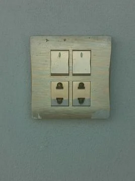 Combination of electrical toggle light switch and power outlet on a green wal Stock Photos
