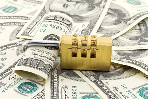 A combination padlock shot over stack of US Dollars banknotes Stock Photos