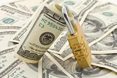 A combination padlock shot over stack of US Dollars banknotes Stock Photos