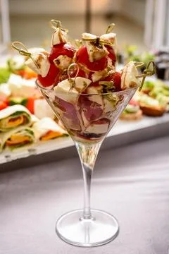 A combination of tomatoes and various types of cheese in a glass cup on the t Photos