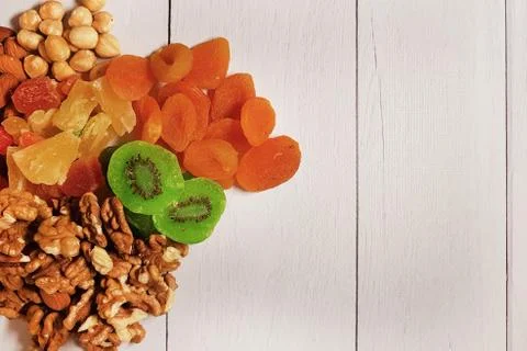 A combination of various nuts and dried fruits and a white wooden table, top Stock Photos