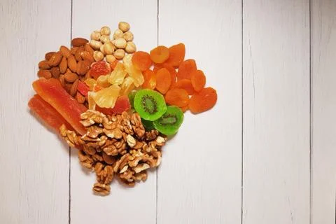 A combination of various nuts and dried fruits and a white wooden table, top Stock Photos
