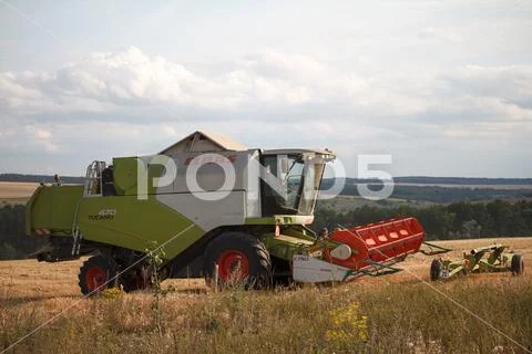 Combine harvester with a raised mechanism rides the stubble after harvesting Stock Photos