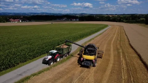 Combine harvester unloading grain into a tractor trailer in a wide landscape Vidéo 340605007