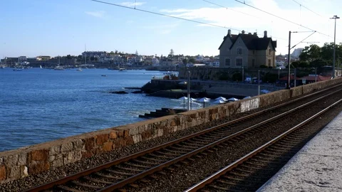 Combios de Portugal train passes the idyllic coastline of Cascais, Portugal Stock Footage 110875567