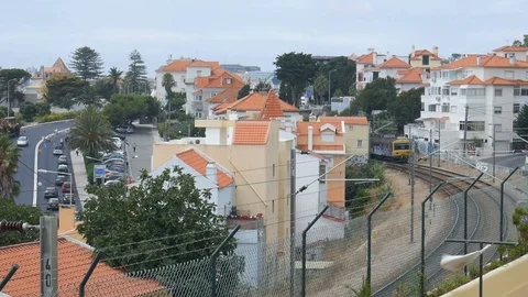 Combois de Portugal train passes on track with Avenida Marginal in background in Stock Footage 113009600