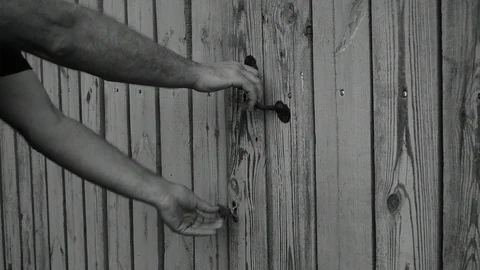 Comes out and closes the gate, black and white Stock Footage 116477484