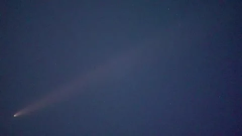 Comet ATLAS shining in the night sky over a horizon with distant lights. Stock Footage 345046759