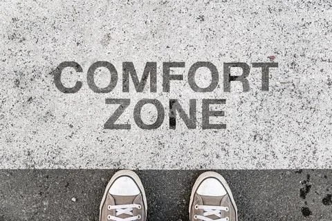 Comfort zone text stenciled on gray pavement with sneakers at the boundary .. Fotos Stock