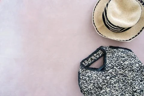 Comfortable beach straw summer hat with black stripes and wicker bag on beige Stock Photos