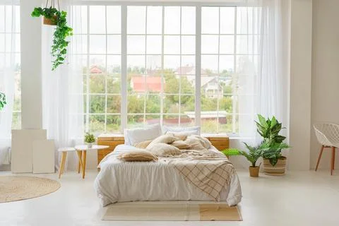 Comfortable bed with lots of soft decorative beige pillows in light sunny b.. Stock Photos