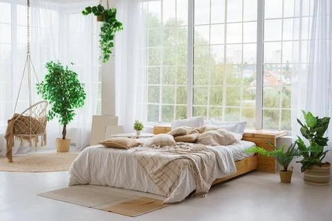 Comfortable bed with lots of soft decorative beige pillows in light sunny b.. Stock Photos