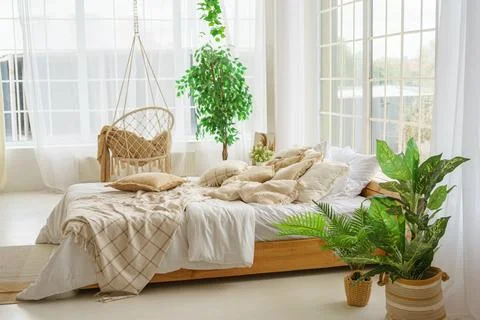 Comfortable bed with lots of soft decorative beige pillows in light sunny b.. Stock Photos