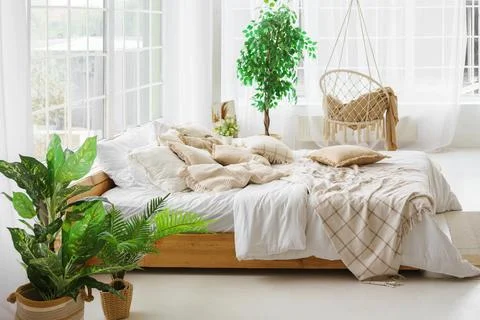 Comfortable bed with lots of soft decorative beige pillows in light sunny b.. Stock Photos