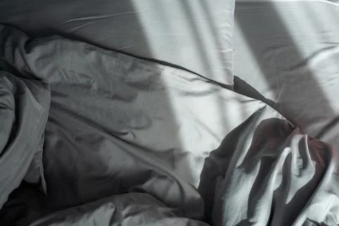 Comfortable bed with pillows and blanket in shady room Stock Photos