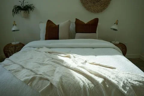Comfortable bed with throw pillows in a bedroom with stylish interior design. Stock Photos