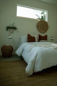 Comfortable bed with throw pillows in a bedroom with stylish interior design. Stock Photos