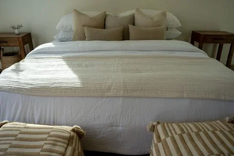 Comfortable bed with throw pillows in a bedroom with stylish interior design. Stock Photos