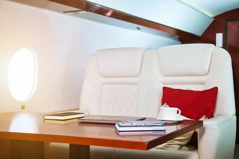 Comfortable chic decor salon private jet with laptop, book, coffee cup on tab Stock-Fotos