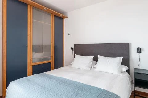 Comfortable double bed and wardrobe in bedroom interior Stock Photos