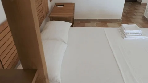 A comfortable double bed is standing on a tiled floor in a hotel room Stock Footage 89915112