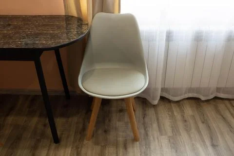 A comfortable gray kitchen chair is standing next to the table. Furniture, .. Stock Photos