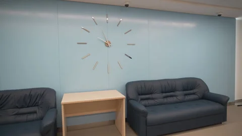 Comfortable hall arranged with soft couches and big clock Stock Footage 317153258