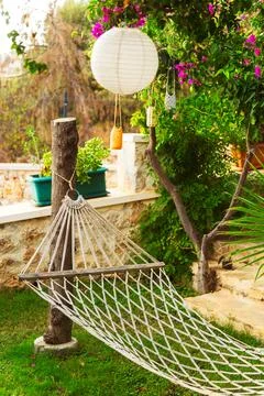 A comfortable hammock is gracefully hanging from a tree in a lovely garden Stock Photos