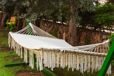 A comfortable hammock is gracefully hanging from a tree in a lovely garden Stock Photos