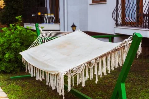 A comfortable hammock is gracefully hanging from a tree in a lovely garden Stock Photos