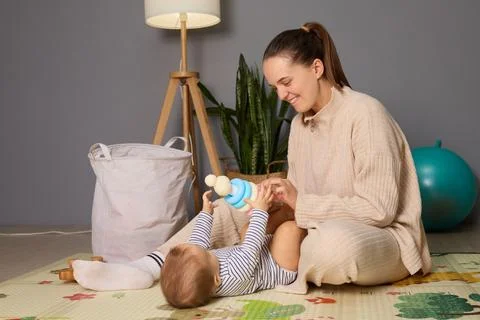 In a comfortable indoor setting, a mother interacts with her baby, who is l.. Stock Photos