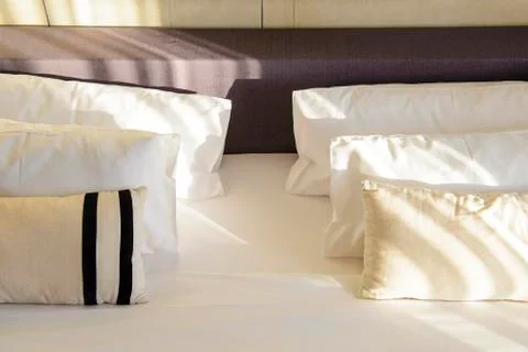 Comfortable pillows and bed with sunlight Stock Photos
