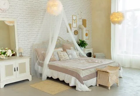 Comfortable simple bedroom with light-colored furniture, four-poster bed, f.. Stock Photos